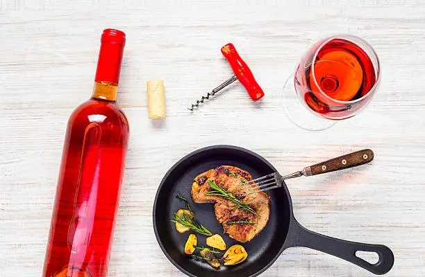 Botella de vino tinto con copa y uvas, resaltando los antioxidantes y el resveratrol presentes en el vino tinto que pueden beneficiar la salud cardiovascular en el contexto de la dieta cetogénica.