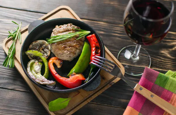 Copa de vino tinto con uvas y un fondo de vid en una mesa rústica, simbolizando el placer y los beneficios del vino en la dieta cetogénica