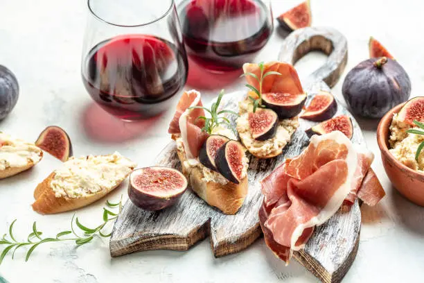 Persona disfrutando de una copa de vino tinto mientras cena con una ensalada fresca y pescado a la parrilla, representando una combinación saludable y equilibrada en una dieta cetogénica